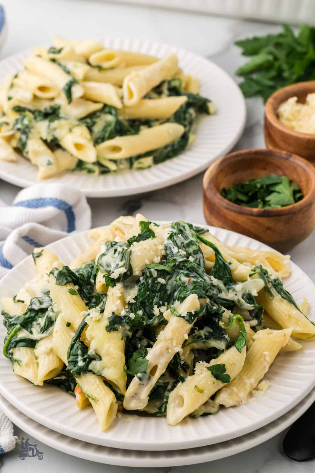 Easy pasta dinner recipe with a creamy spinach sauce served on white dinner plates.