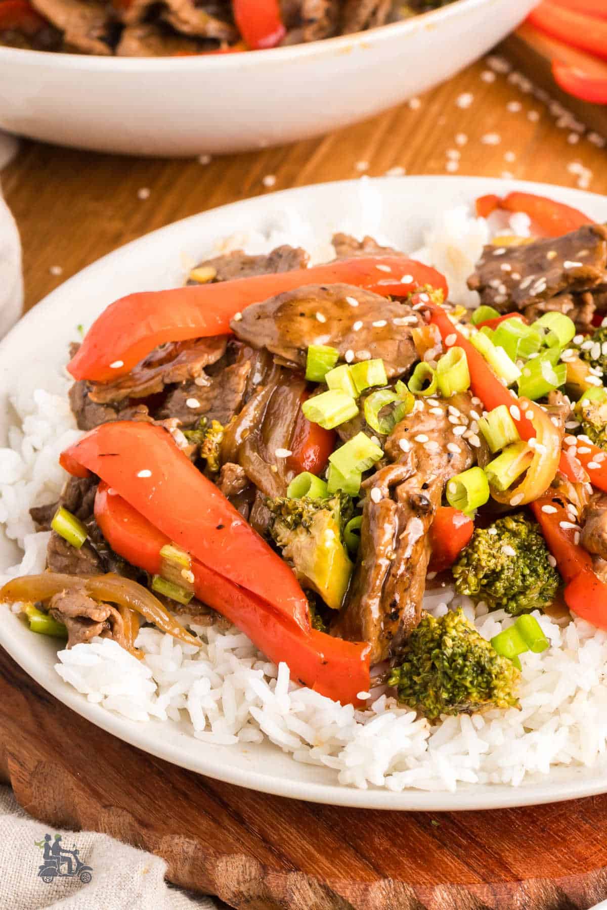 Flavorful beef stir fry served in a bowl over steamed rice and sprinkled with sesame seeds.