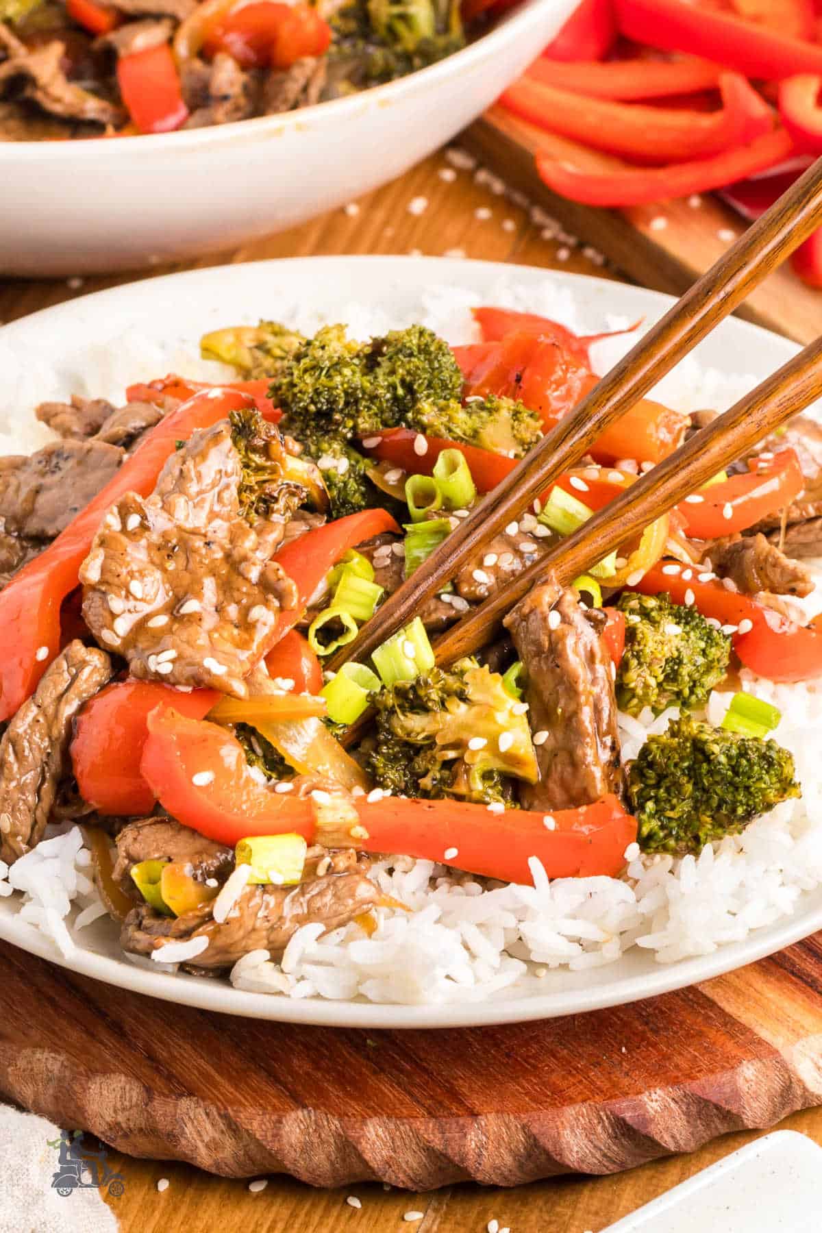 Close-up of teriyaki beef with crisp vegetables coated in savory sauce and served with chopsticks.