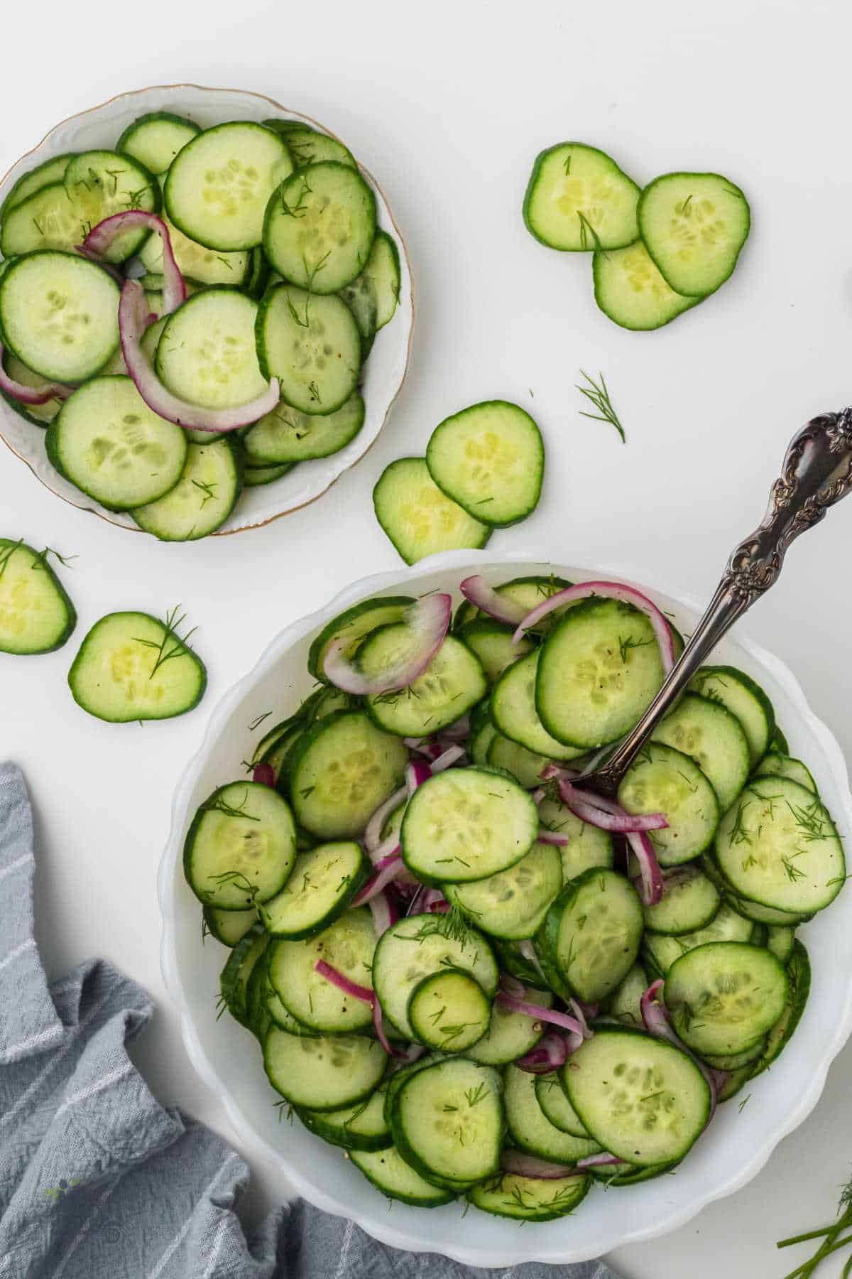 Overhead view of a cucumber salad in a bowl with a serving spoon in the easy side salad.