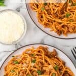 Long Pinterest pin with spaghetti tossed with meat sauce in pasta bowls.