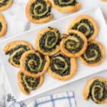 The cream cheese puff pastry appetizers on a serving plate with several appetizers on the table.