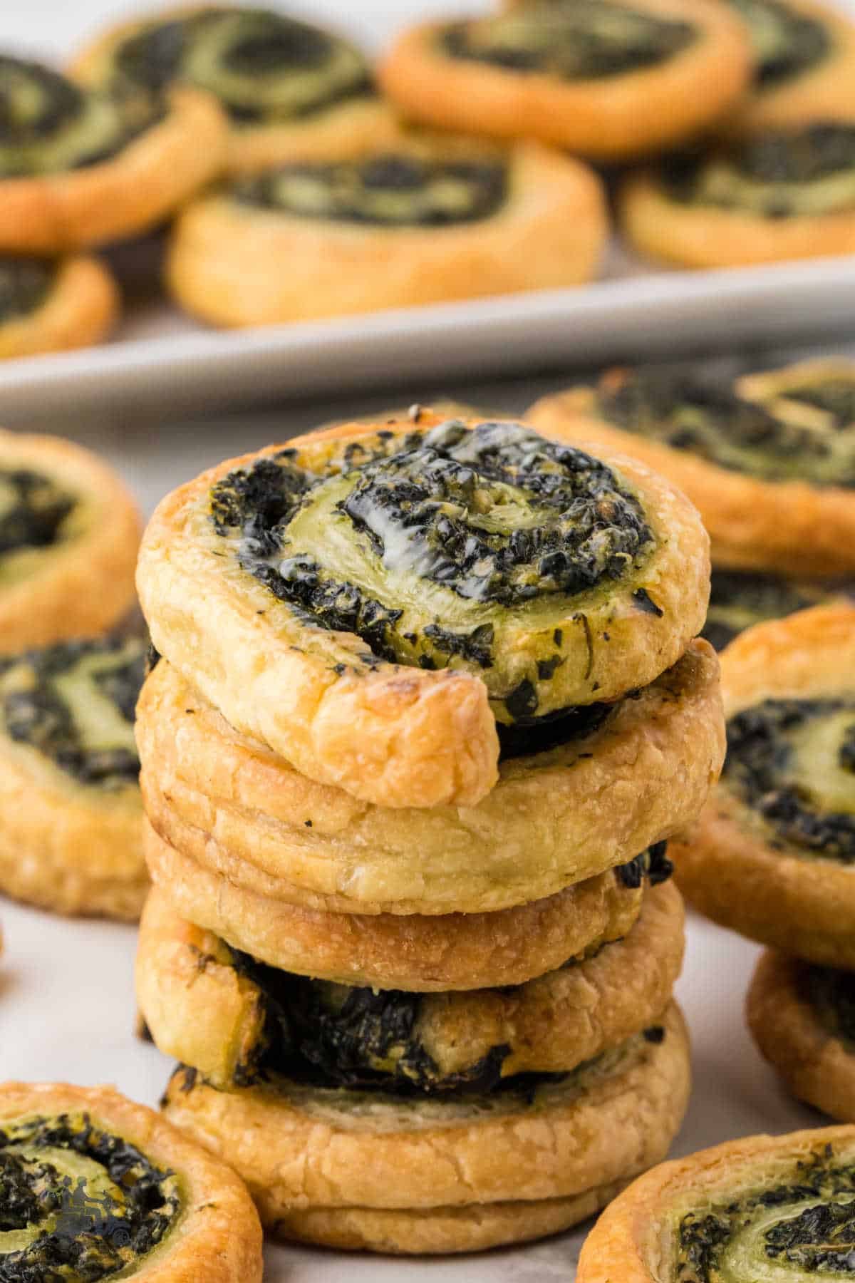 A stack of the pinwheel appetizers made with spinach, cheese, and puff pastry, ready to be served.