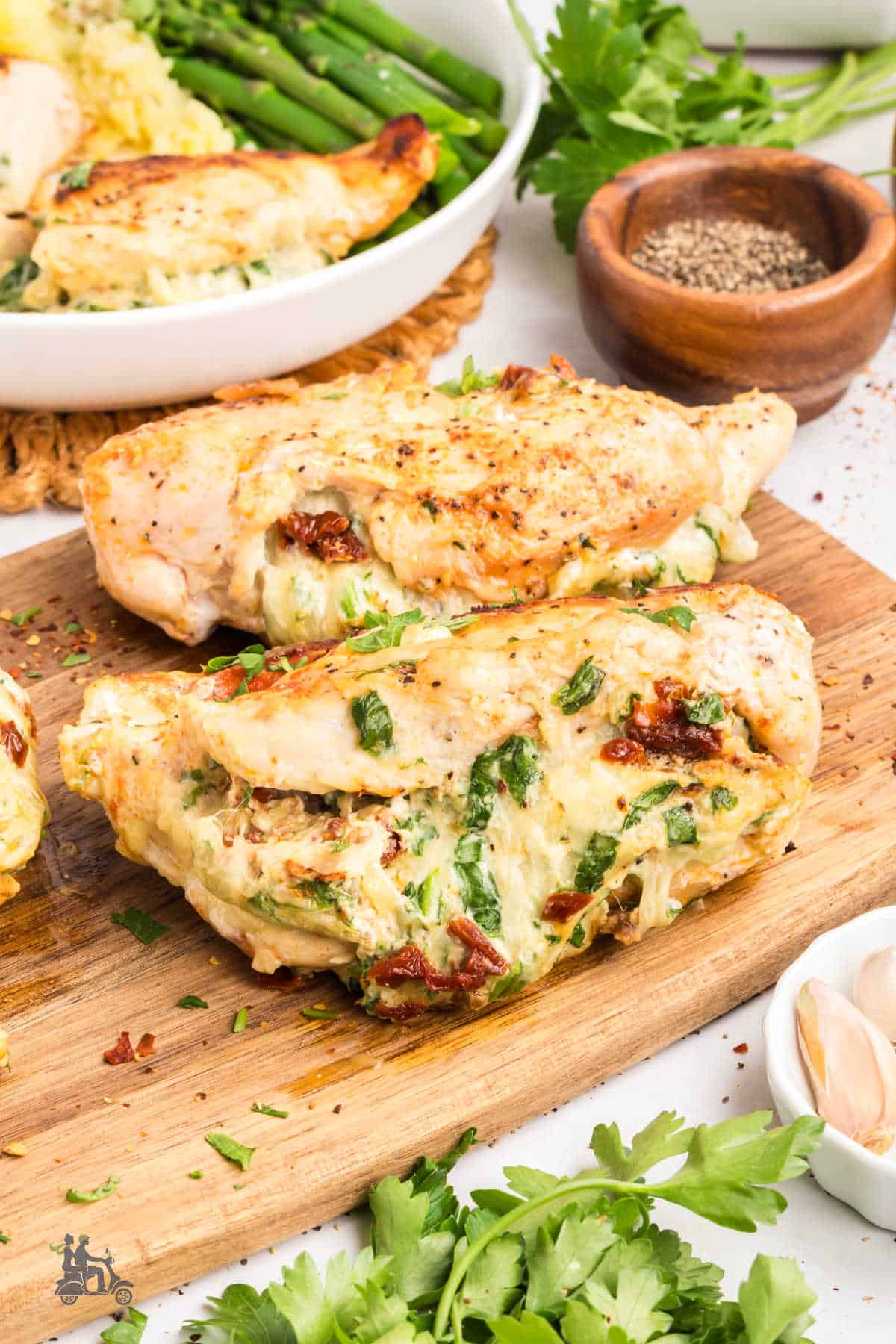 One-skillet creamy spinach stuffed chicken breasts on a wood cutting board.