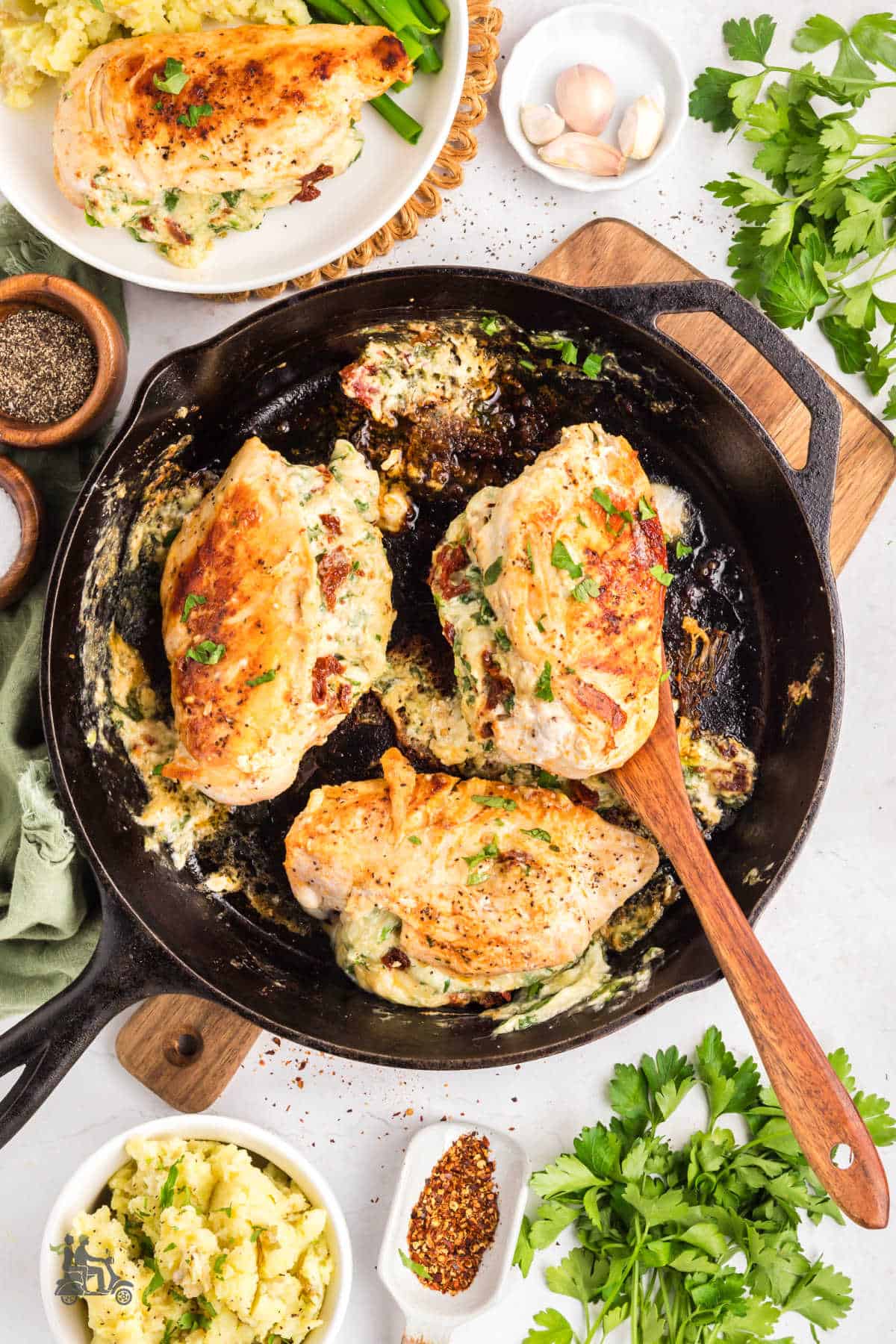 Creamy spinach and cheese stuffed chicken breasts cooked in a black skillet with a spatula, removing one breast.