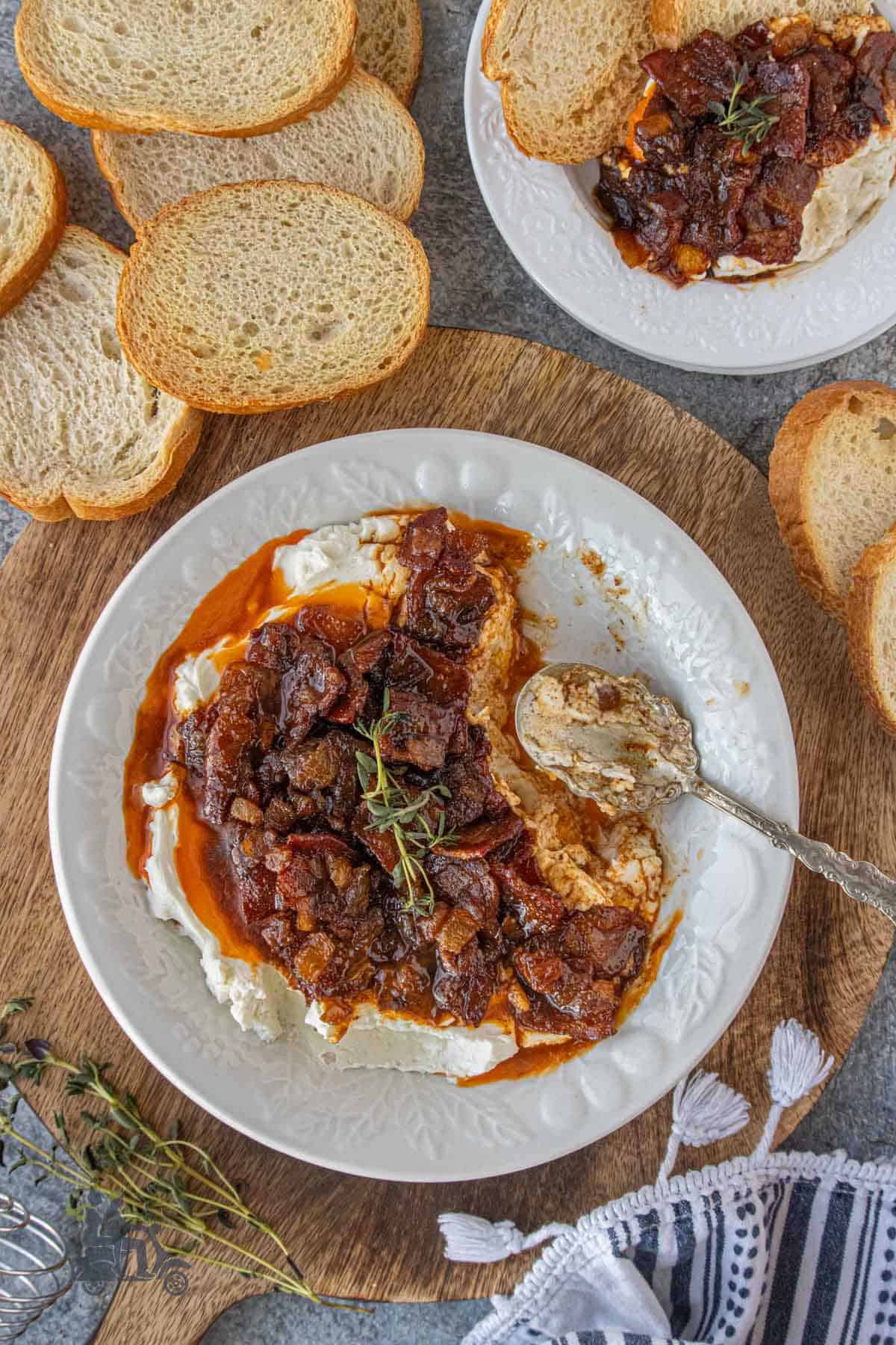 Creamy goat cheese appetizer with caramelized bacon onion jam in a shallow serving bowl with a spoon.