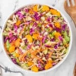 Salad bowl filled with mandarin orange chicken salad topped with sliced almonds, green onions, and mixed with crunchy ramen noodles.
