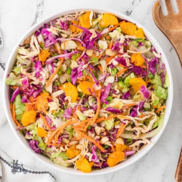 Salad bowl filled with mandarin orange chicken salad topped with sliced almonds, green onions, and mixed with crunchy ramen noodles.