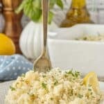 Close up of white Italian seasoned rice served on a white plate with a fork standing in the middle of the dish.