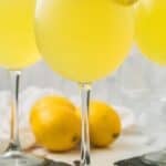Spoonful of melting lemon sorbet floating in a sparkling limoncello cocktail for a bright summer beverage.