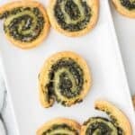 Puff pastry pinwheels with spinach and cream cheese appetizer on a white serving dish.