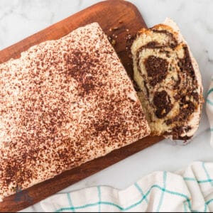 Tiramisu Quick Bread with Mascarpone frosting on a cutting board with a bread slice showing.