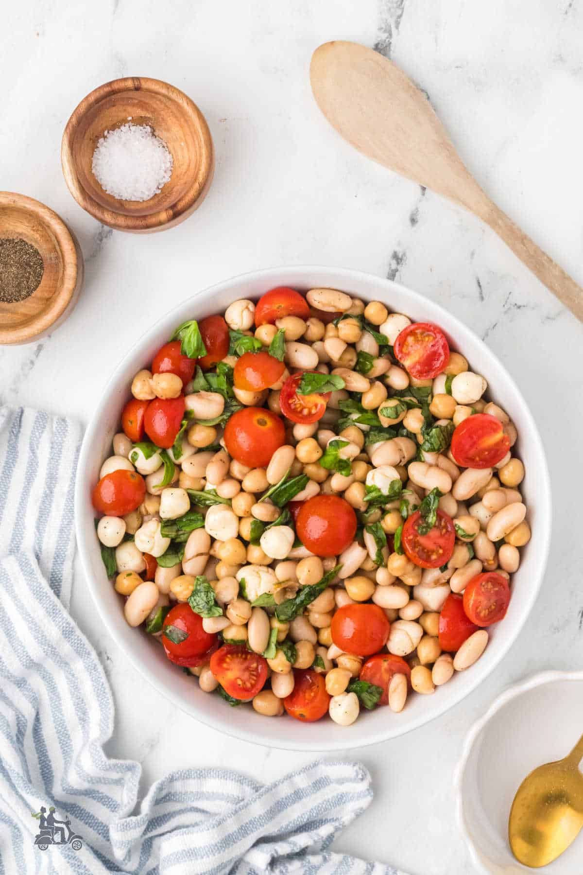 Dense Caprese Bean Salad ingredients tossed together in a large white serving bowl.
