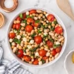 Close-up of chickpeas, white beans, tomatoes, mozzarella pearls, and torn basil in Caprese Bean Salad.
