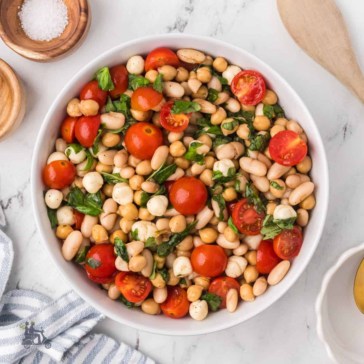 Close-up of chickpeas, white beans, tomatoes, mozzarella pearls, and torn basil in Caprese Bean Salad.