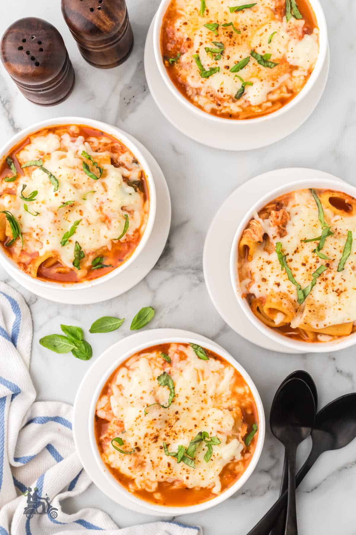 Overhead view of homemade Parm Chicken Cheesy soup garnished with Mozzarella cheese and fresh basil.