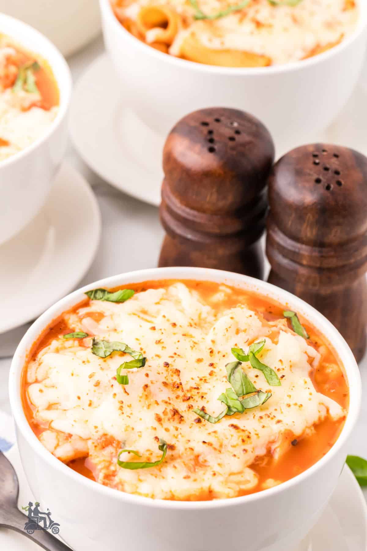 Italian-inspired Chicken Parmesan Soup served in a white bowl on a white table.