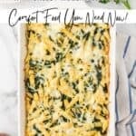 Baked penne with creamed spinach, cream cheese, and mozzarella cheese in a white baking dish.