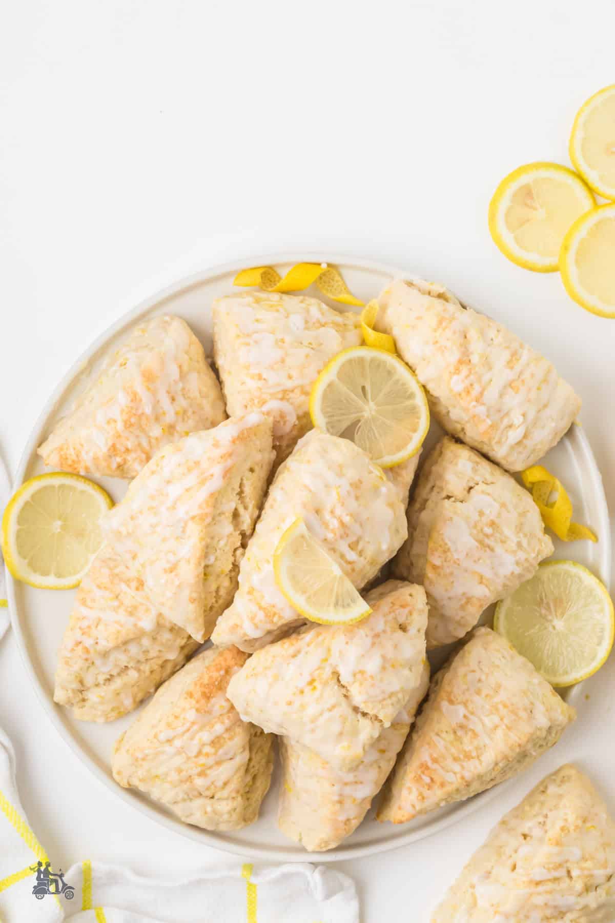 Make ahead lemon scones with lemon glaze stacked on a white serving tray.