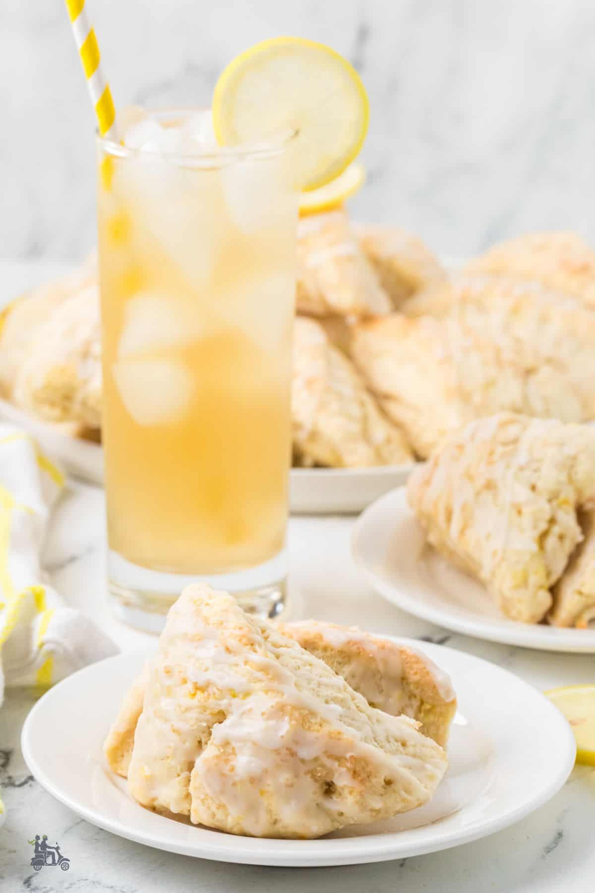 Freshly baked scone drizzled with lemon glaze and served on a white dessert plate.