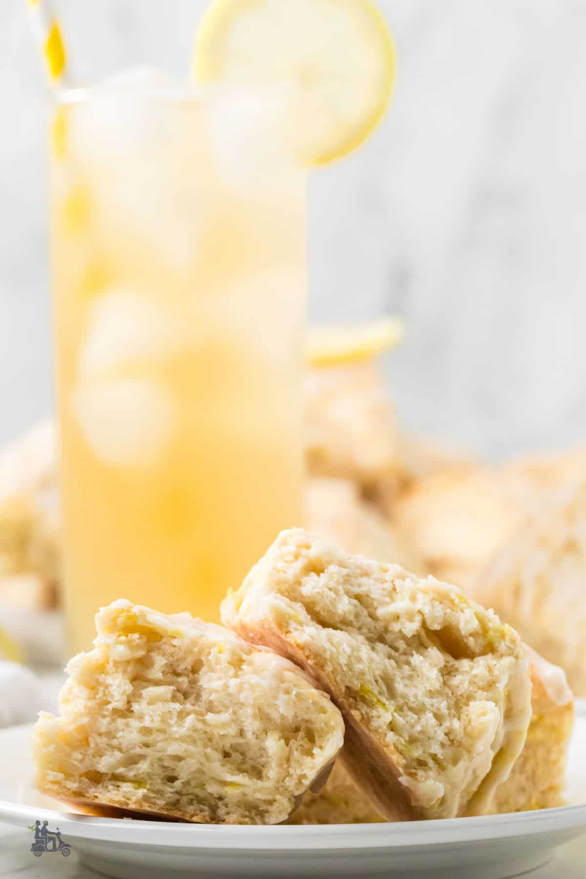 Bakery-style lemon scones split in half to show the flaky interior and served with iced cold lemonade.