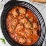 A Crockpot filled with beef and sausage meatballs bathed in homemade tomato sauce.