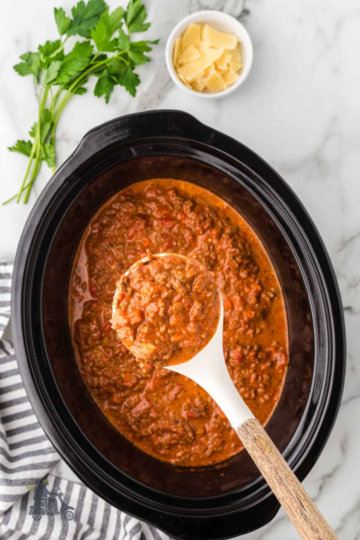 Homemade Bolognese Sauce made in the crockpot with a ladle removing a large helping.