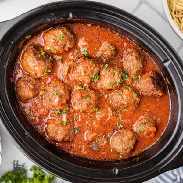 Homemade slow cooker meatballs simmered in chunky tomato sauce with seasoned herbs.