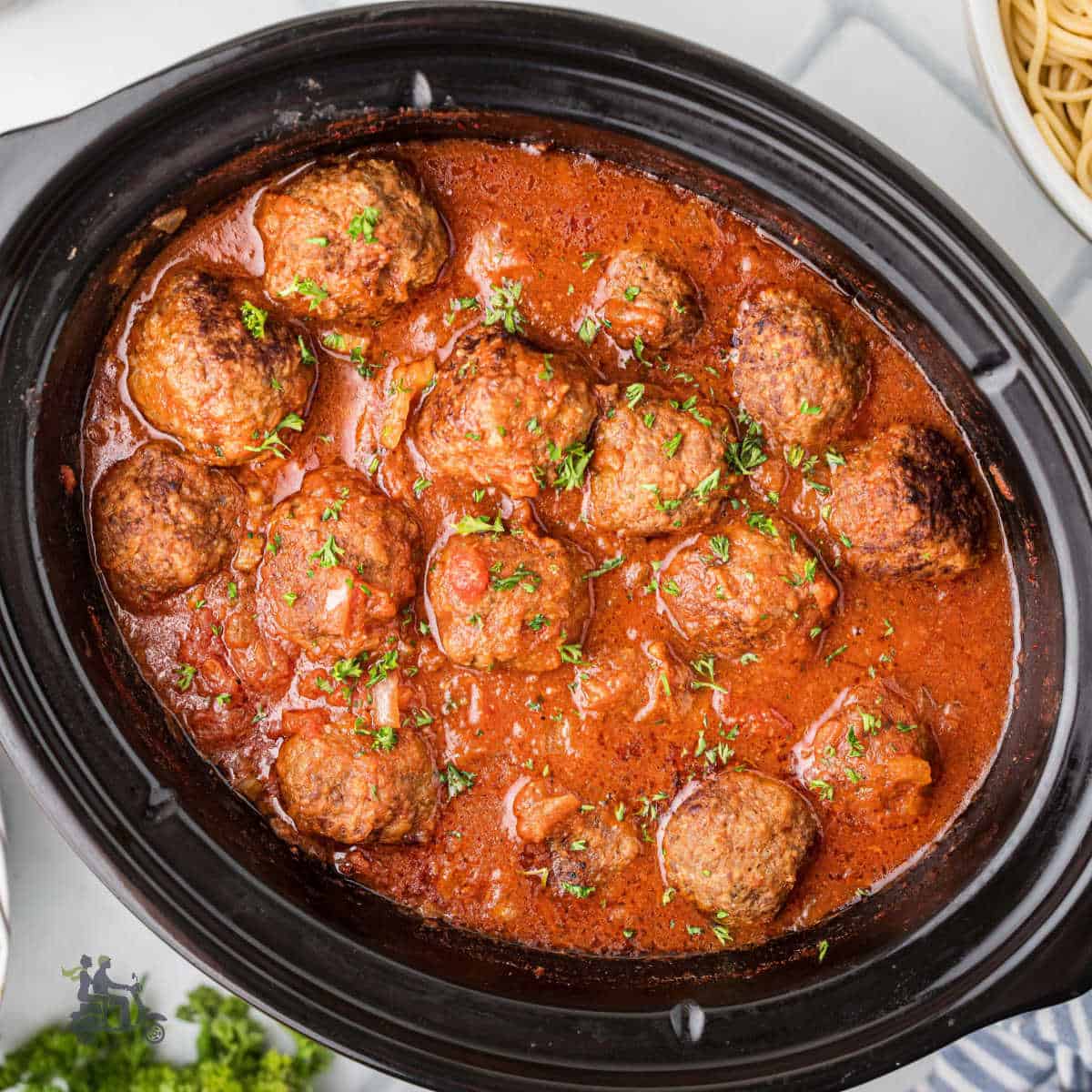 Homemade slow cooker meatballs simmered in chunky tomato sauce with seasoned herbs.
