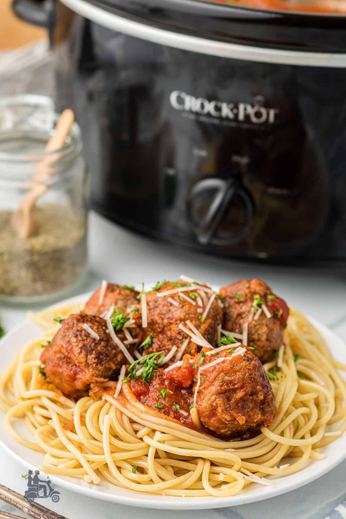 Homemade slow cooker meatballs plated for dinner with pasta and more seasoning on the side.