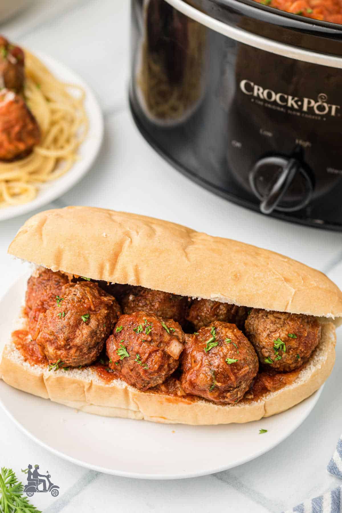 Juicy homemade crockpot meatballs tucked into a sub roll with Italian parsley sprinkled on top.
