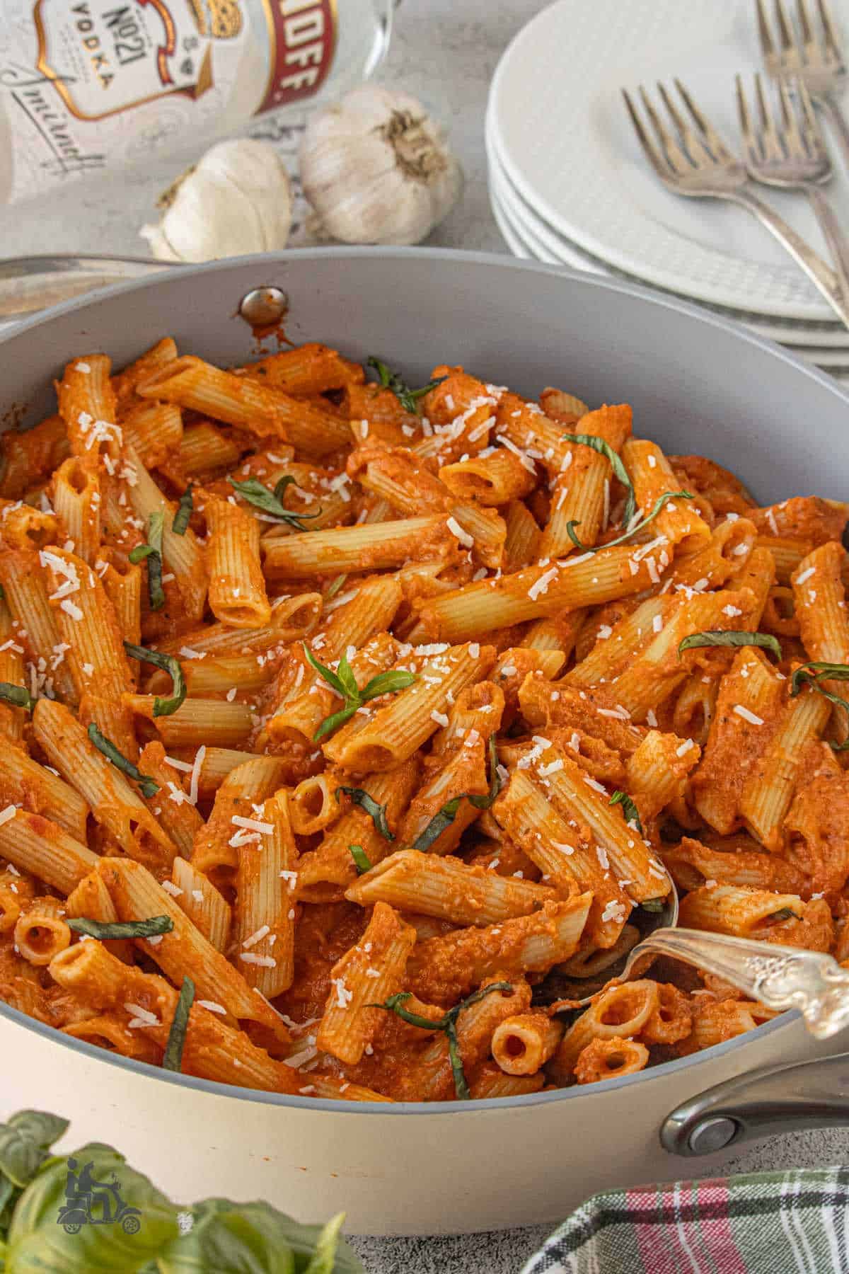 Large deep braiser filled with penne pasta mixed with a silky vodka sauce and sprinkled with parmesan and chopped basil.