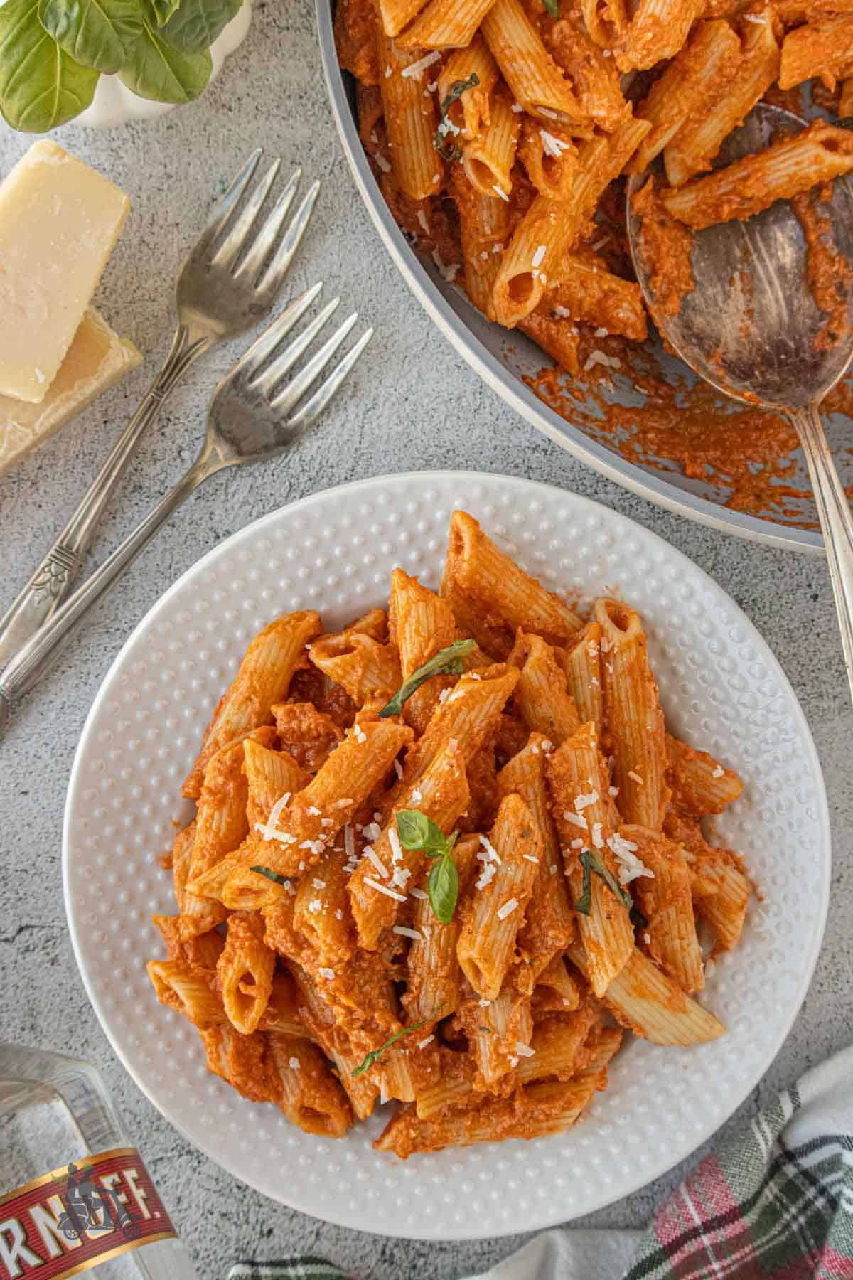 Creamy San Marzano Vodka Sauce recipe served with penne pasta and garnished with Parmesan cheese and fresh basil. 