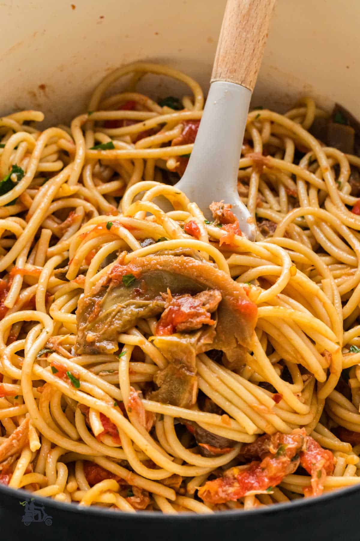 Pasta fork lifting strands of tuna spaghetti with tomato sauce and fresh parsley.