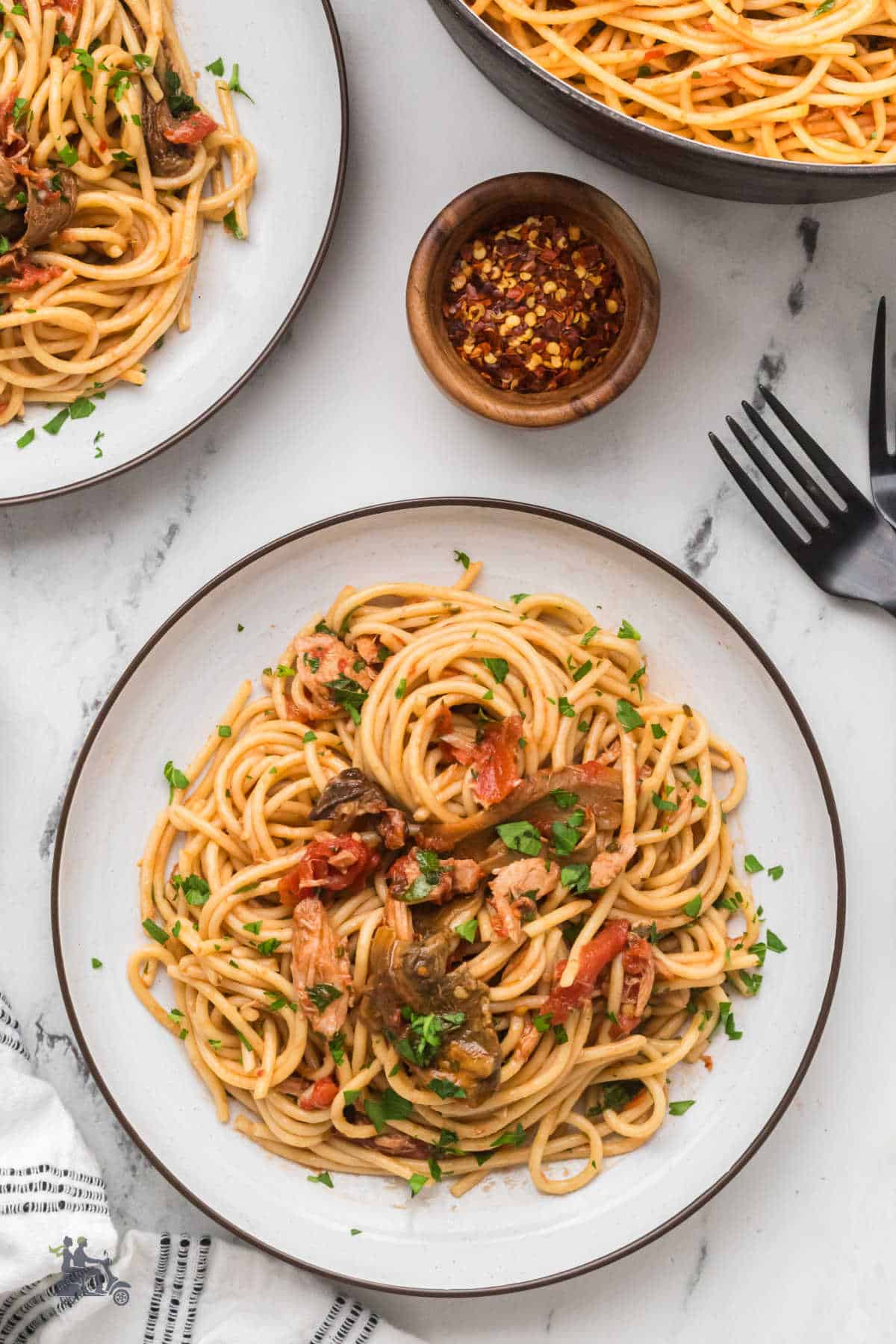 Spaghetti alla Carrettiera with tuna and mushrooms served in a shallow white and brown bowl. 