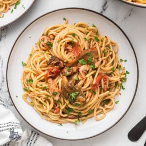 Roman-Style tuna spaghetti with tomato sauce, porcini mushrooms, and chopped parsley.