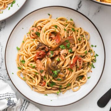 Roman-Style tuna spaghetti with tomato sauce, porcini mushrooms, and chopped parsley.