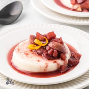Close-up of creamy buttermilk panna cotta topped with ruby port fruit sauce.