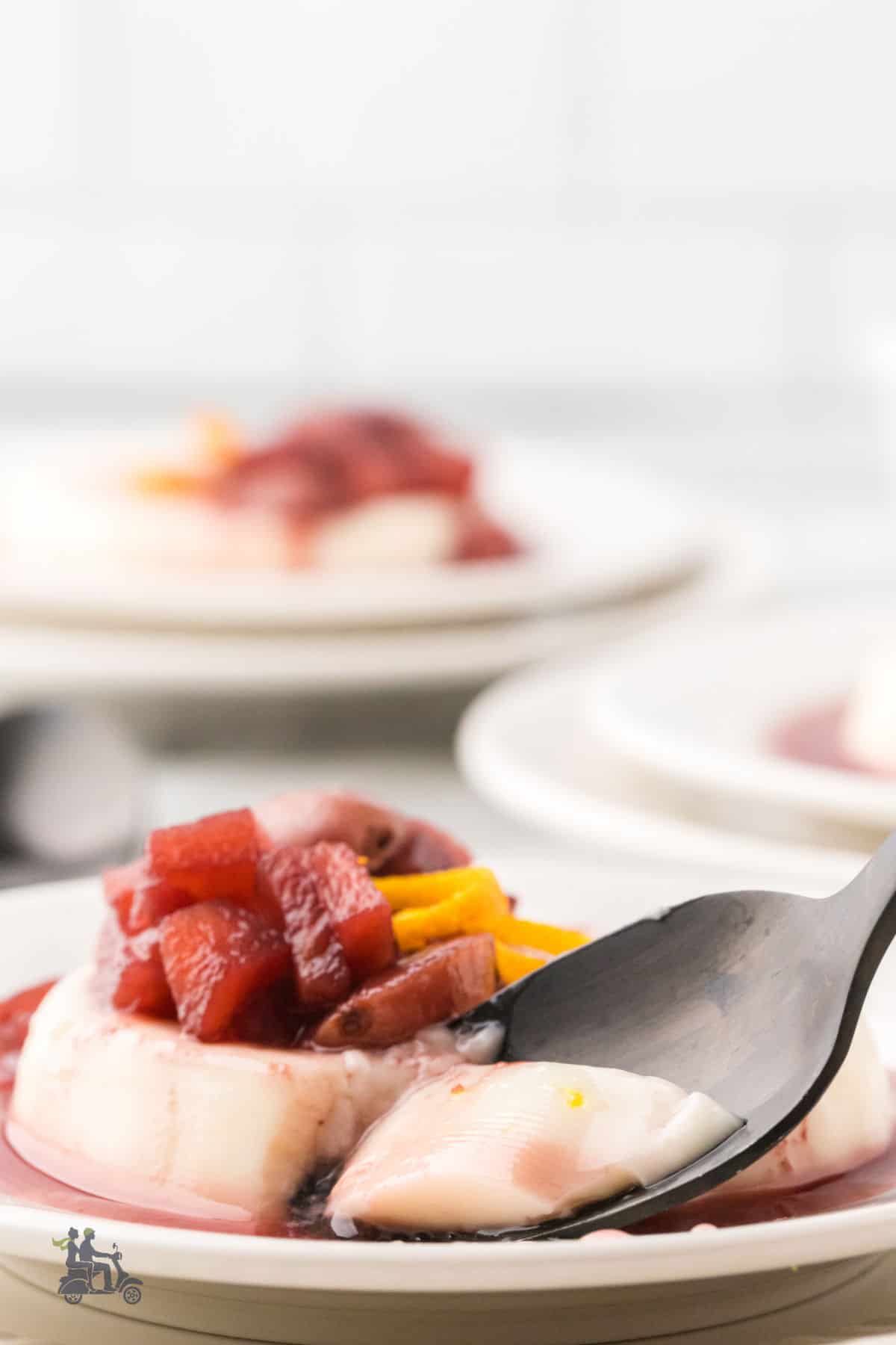 Spoonful of buttermilk panna cotta with poached apple, pear, and grape in wine sauce.