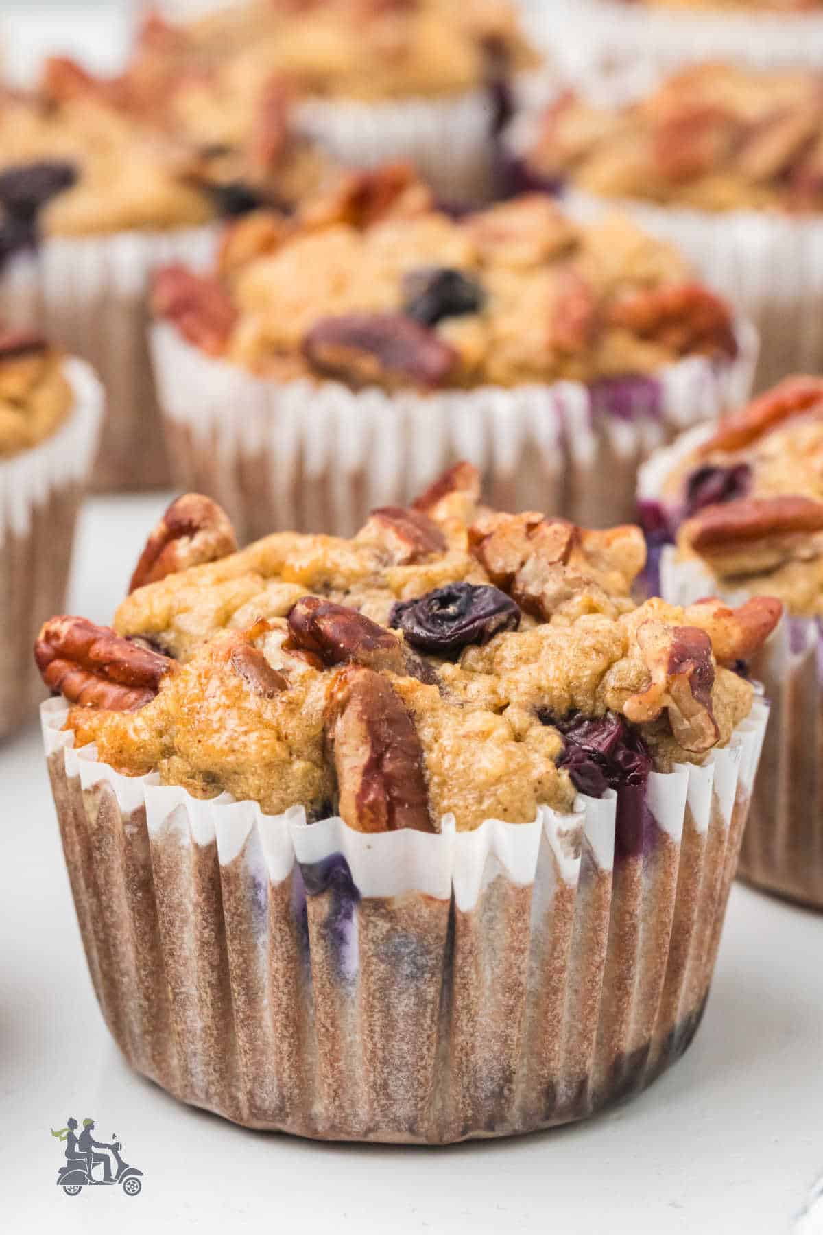 Closeup of a Pecan and Blueberry topped muffin in a paper muffin cup.