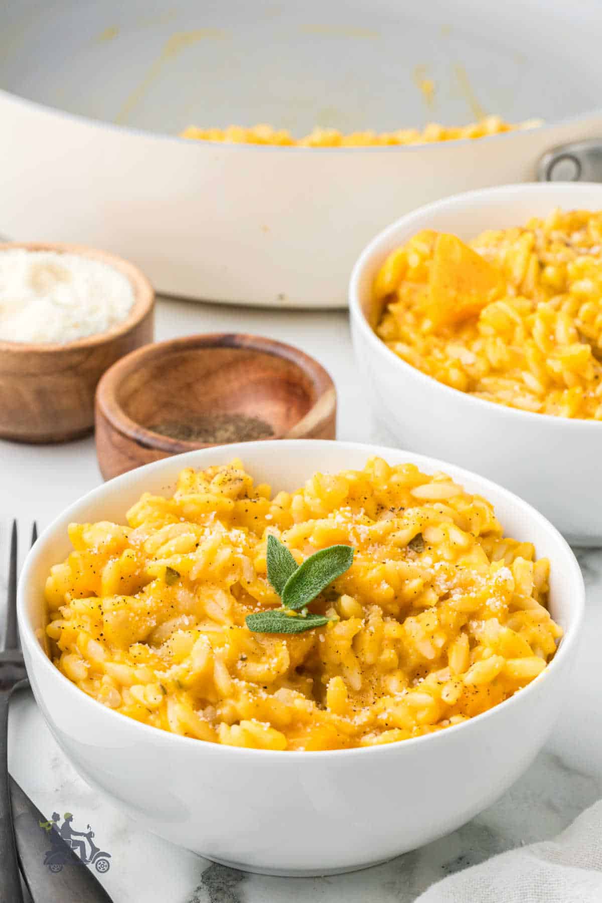 White bowls filled with creamy orzo risotto made with butternut squash, sage, and parmesan cheese. 