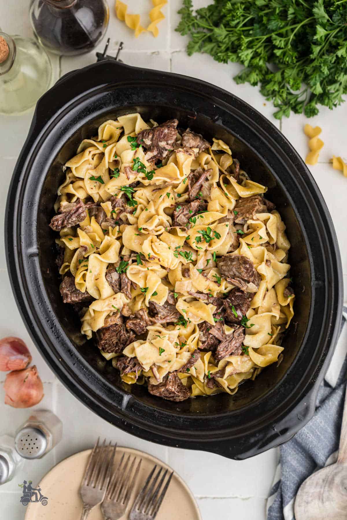 Cubed beef and egg noodles cook in a slow cooker covered in a rich gravy. 
